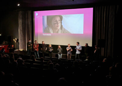 Das Team des Kurzfilms "Tischrebellen" vor der Leinwand. Der Film basiert auf dem Drehbuch "Tischmanieren", mit dem Autor*innen Linn und Luka Peltzer 2019 den Publikumspreis gewannen.