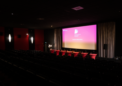 Noch leerer Saal 1 im Kieler Studio Filmtheater mit Sitzplätzen für die Lesenden und Logo vom Drehbuchpreis Schleswig-Holstein im Hintergrund.